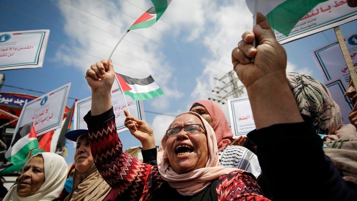 Palestinian women lift national flags and placards during a rally for supporters of the Fateh movement against Israel's West Bank annexation plans, in Beit Hanun in the north of the Gaza Strip, July 6, 2020. (AFP)