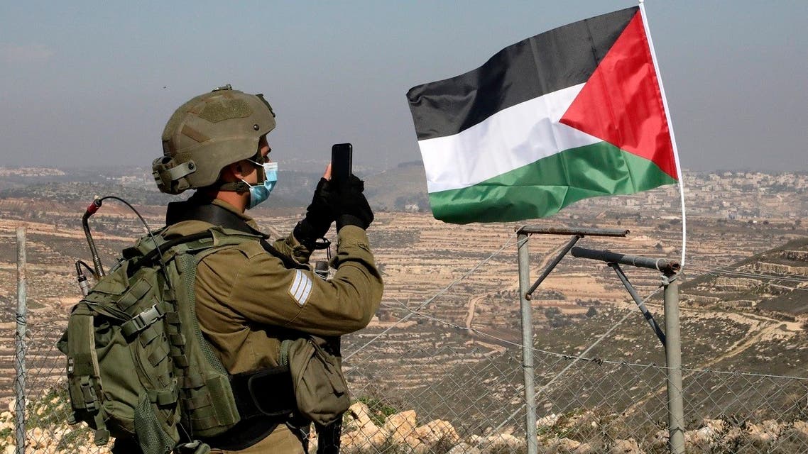 A member of Israel's security forces takes pictures as Palestinian demonstrators try to reach their lands confiscated by Israeli authorities, in the occupied West Bank, Jan. 4, 2021. (AFP)