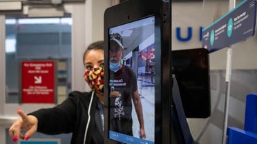 A United Airlines employee helps a passenger position himself as he uses biometric boarding to board an international flight from IAH George Bush Intercontinental Airport, July 21, 2020. (Reuters)