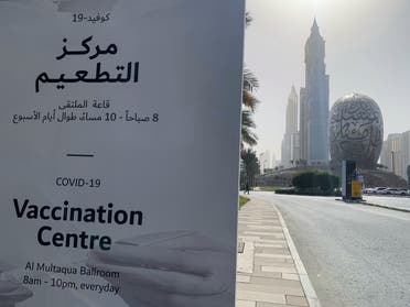 An advertisement placard informs the public of the location of a designated COVID-19 vaccination center at Dubai's financial center district, UAE. (AFP)