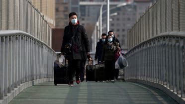 People wearing face masks to help curb the spread of the coronavirus walk with their luggage over a pedestrian bridge to the railway station to catch their trains in Beijing, Wednesday, Jan. 27, 2021. (AP)