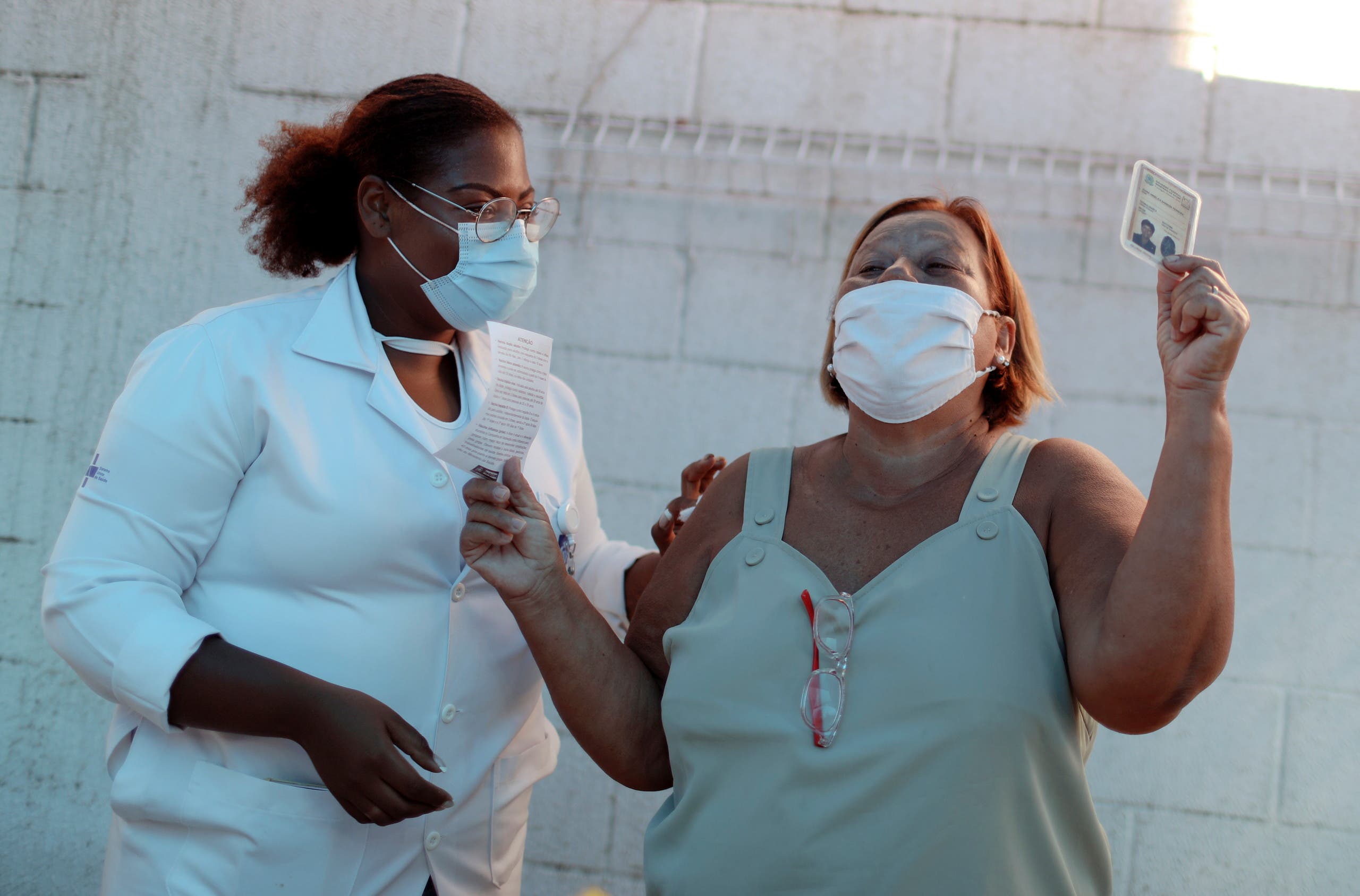 ممرضة تشهر بطاقة التطعيم بعد تلقيها لقاح كورونا في البرازيل