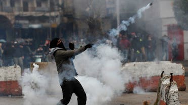 A protester throws back a tear gas canister towards riot policemen during a protest against deteriorating living conditions and strict coronavirus lockdown measures, in Tripoli, Jan. 28, 2021. (AP)