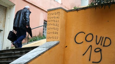 man walks up public stairs past graffiti relating to the coronavirus (COVID-19). (AFP)