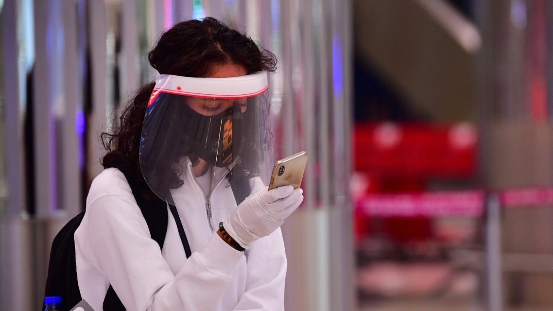 A tourist checks her phone as she wait to get a medical screening upon arrival at Teminal 3 at Dubai airport. (AFP)