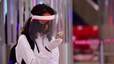 A tourist checks her phone as she wait to get a medical screening upon arrival at Teminal 3 at Dubai airport. (AFP)