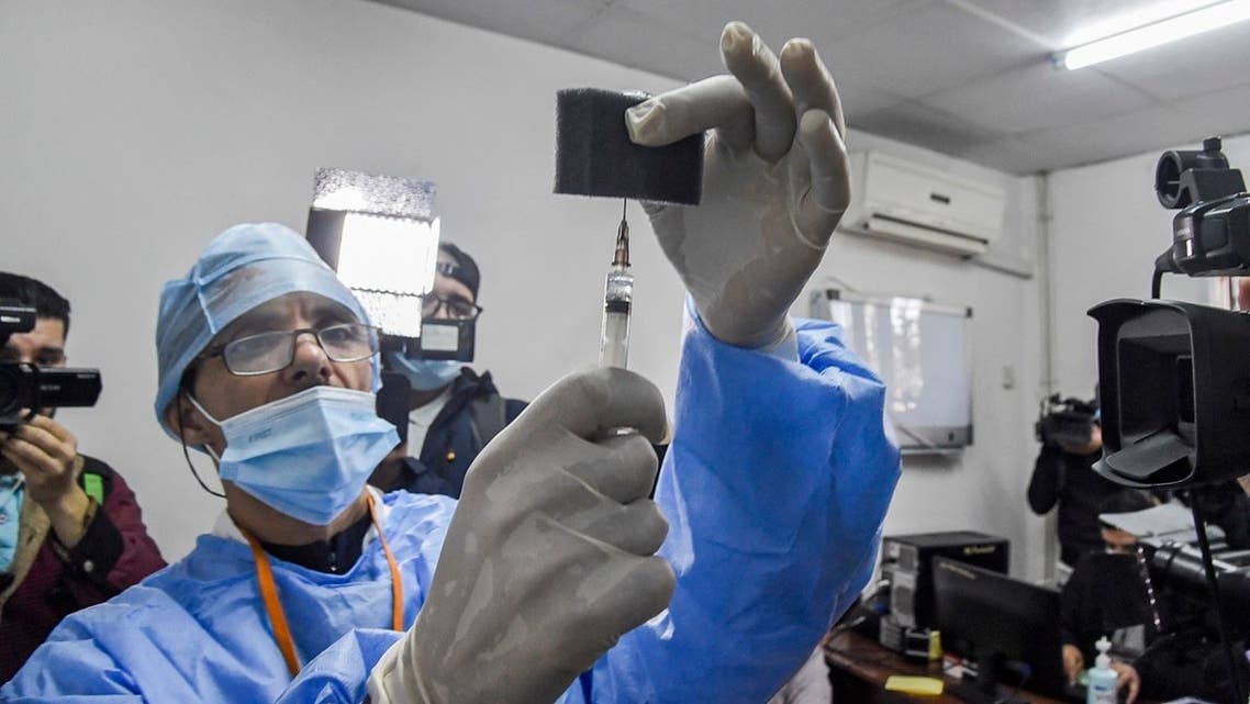 Journalists huddle around a medic about to administer a dose of Russia’s Sputnik V vaccine at a clinic in the city of Blida, southwest of the Algerian capital, January 30, 2021. (Ryad Kramdi/AFP)