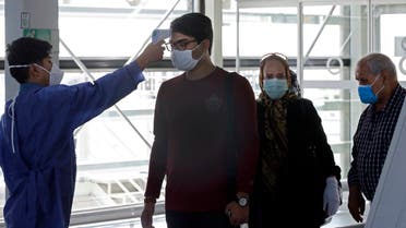 An airport worker checks the body temperature of incoming passengers upon arrival at the Iranian capital Tehran's Imam Khomeini International Airport on July 17, 2020. (AFP)