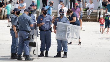 Members of the South African Police Services with riot shields patrol during a coronavirus-protest against the government’s ban on people enjoying the beach in Cape Town’s Muizenberg district on January 30, 2021. (Rodger Bosch/AFP)