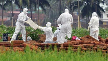 Doctors and relatives wearing protective gear dig a grave to bury the body of a victim, who lost his battle against the brain-damaging Nipah virus, in the southern Indian state of Kerala, India, May 24, 2018. (Reuters)