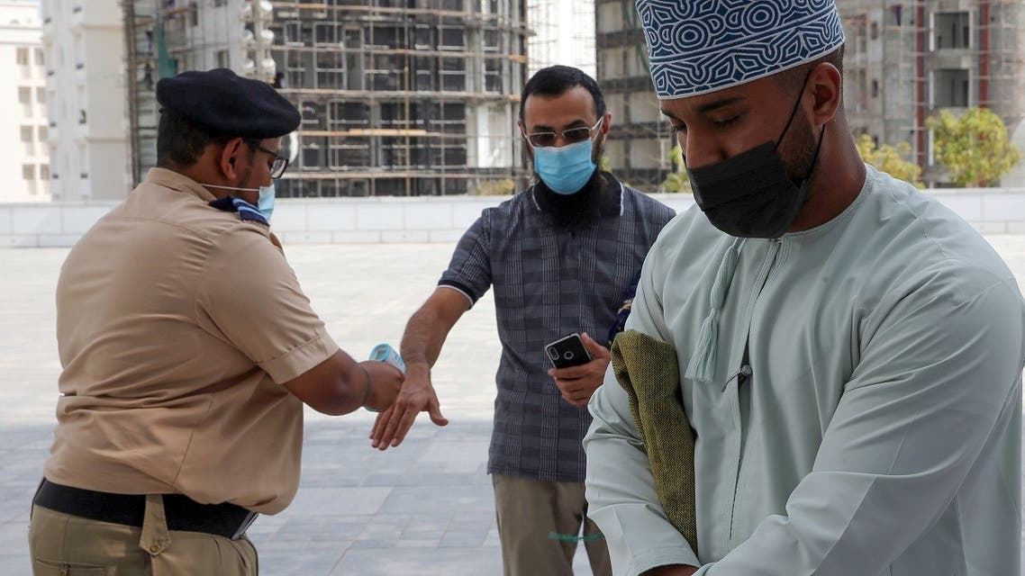 Mask-clad men use disinfecting gel and get their temperature checked before entering the Mohammed al-Amin Mosque in the Omani capital Muscat, November 15, 2020. (Mohammed Mahjoub/AFP)