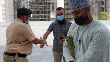 Mask-clad men use disinfecting gel and get their temperature checked before entering the Mohammed al-Amin Mosque in the Omani capital Muscat, November 15, 2020. (Mohammed Mahjoub/AFP)