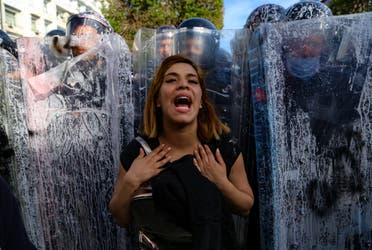 A Tunisian woman reacts as she stand in front of police officers forming a human shield to block the access to demonstrators to the the interior ministry in the capital Tunis. (AFP)