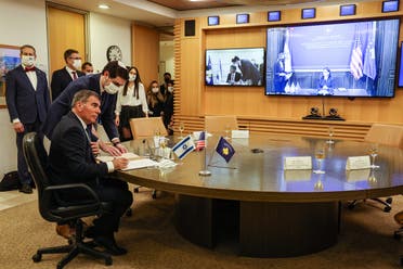 Israel’s FM Gabi Ashkenazi (L) signs the joint declaration establishing ties with Kosovo during an official ceremony held over Zoom with his counterpart from Kosovo Meliza Haradinaj Stublla (screen), at the Israeli Foreign Ministry headquarters in Jerusalem on February 1, 2021. (Menahem Kahana/AFP)