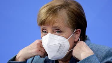 German Chancellor Angela Merkel removes her face mask ahead of a news conference in Berlin, on February 1, 2021. (AFP)