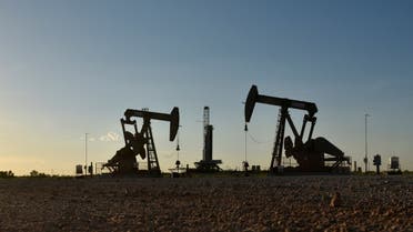 Pump jacks operate in front of a drilling rig in an oil field in Midland, Texas, US. (Reuters)