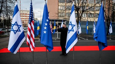 A Kosovo Albanian man takes pictures of Israeli’s, US and Kosovo’s flag displayed during a ceremony at the headquarters of the Foreign Ministry in Pristina on February 1, 2021. (Armend Nimani/AFP)