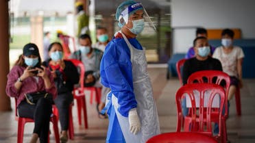 A medical worker wearing protective suits stand beside people waiting for their turn for coronavirus testing at a center for private COVID-19 testing in Petaling Jaya, Malaysia, on Monday, Feb. 1, 2021. (AP)