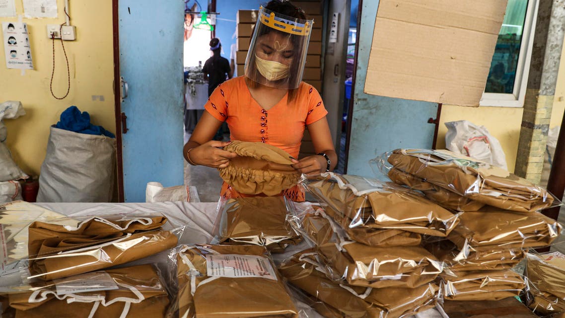 A woman wearing face mask and shield to help curb the spread of the new coronavirus checks surgical gown at a packing session of a garment factory at Industrial Zone in Yangon, Myanmar. (File photo: AP)