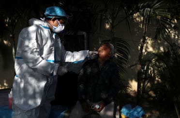 A healthcare worker wearing personal protective equipment (PPE) collects a swab sample from a man amidst the spread of the coronavirus disease (COVID-19), at a bus depot in New Delhi, India, December 14, 2020. (Reuters)