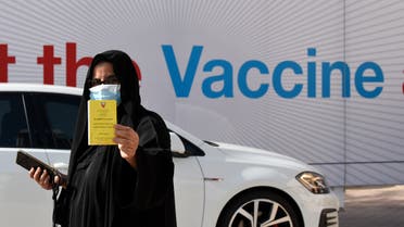 A woman displays her COVID-19 vaccine certificate in front of the Bahrain International Exhibition and Convention Center in the capital Manama, on December 24, 2020. (AFP)
