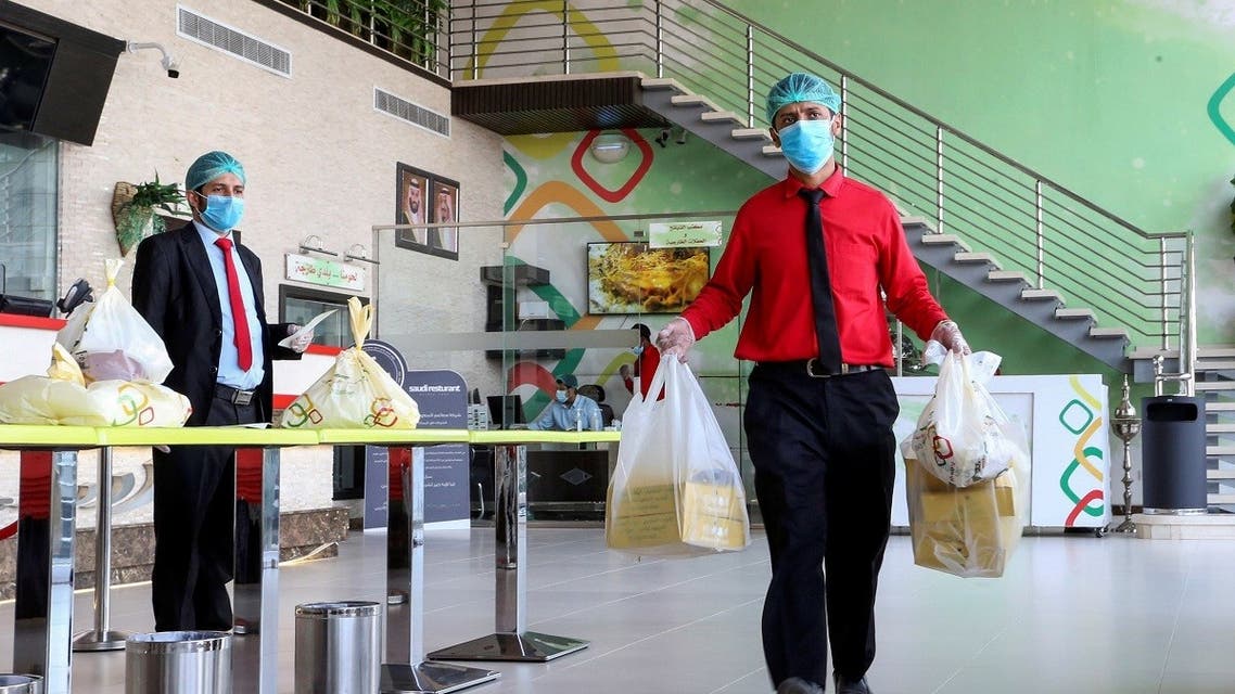 A food delivery worker wearing protective face mask and gloves, following the outbreak of the coronavirus disease (COVID-19), carries Ramadan meal orders at a restaurant in Riyadh, Saudi Arabia April 26, 2020. (Reuters)