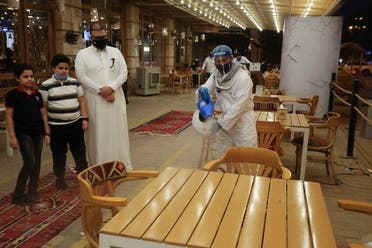 A worker wears a protective suit, following the outbreak of the coronavirus disease (COVID-19), sterilizes the tables before the customers sit down after a restaurant reopened, in Riyadh. (Reuters)