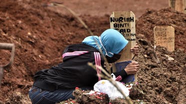 A woman grieves over the grave of a loved one who died of the COVID-19 coronavirus at a cemetery in Bekasi on January 28, 2021, after Indonesia passed more than one million coronavirus cases on January 26. (AFP)