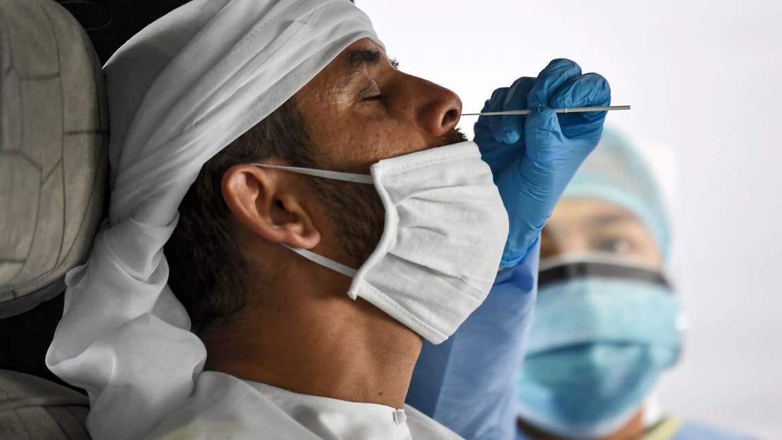 A medical staff member obtains a swab sample from a man inside a vehicle at a drive-through COVID-19 coronavirus testing centre in al-Khawaneej district of the gulf emirate of Dubai. (AFP)
