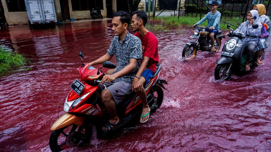People ride motorbikes through a flooded road with red water due to the dye-waste from cloth factories, in Pekalongan, Central Java province, Indonesia. (Reuters)
