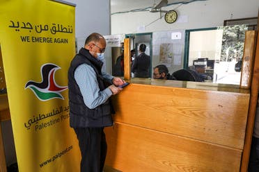 A man is assisted at a post office in the city of al-Bireh, about 15 kilometers north of Jerusalem in the occupied West Bank, on February 7, 2021. (Abbas Momani/AFP)