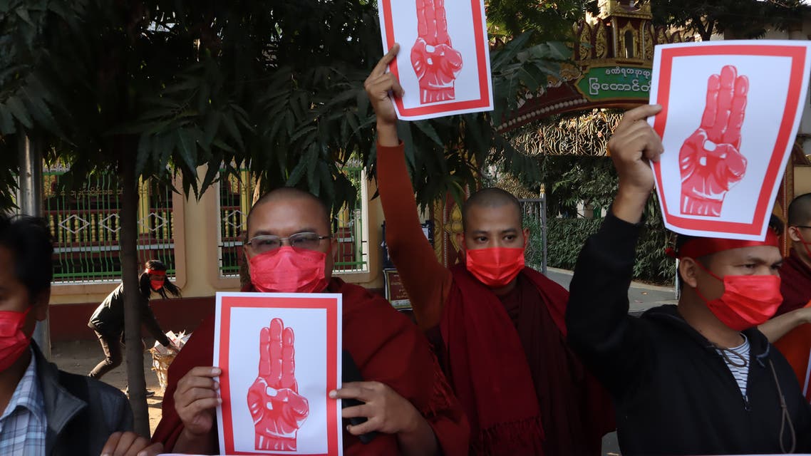 Buddhist monks hold signs showing the three finger salute during a demonstration against the military coup in Mandalay on February 8, 2021.