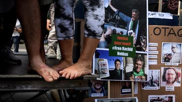 Activists close to the Hirak Algerian protest movement stand barefoot next to photos of prisonners during a demonstration in front of the United Nations Offices in Geneva against the arbitrary arrests in Algeria. (File photo: AFP)