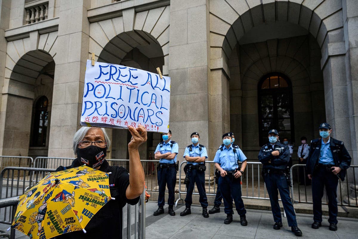 A pro-democracy activist (L) holds up a placard as police stand guard outside the Court of Final Appeal in Hong Kong on February 1, 2021, during a bail hearing for detained media tycoon Jimmy Lai. (AFP)