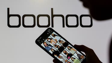 202A woman poses with a smartphone showing the Boohoo app in front of the Boohoo logo on display. (Reuters)1-02-08T072922Z_444033007_RC27OL9VQJZJ_RTRMADP_3_ARCADIA-M-A-BOOHOO