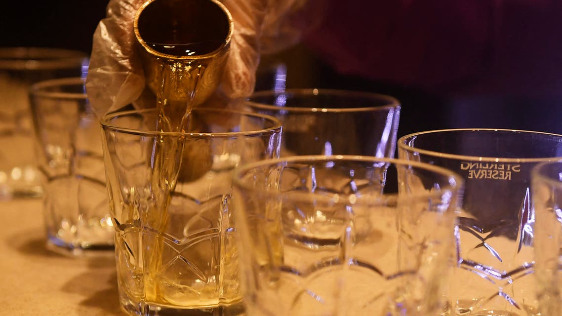 A bartender makes drinks for customers inside a bar. (AFP)