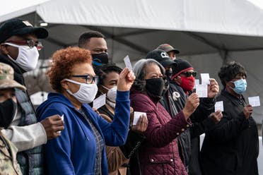 A group of people show off their coronavirus vaccine record cards in the parking lot of Six Flags on February 6, 2021 in Bowie, Maryland, US. (AFP)