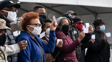 A group of people show off their coronavirus vaccine record cards in the parking lot of Six Flags on February 6, 2021 in Bowie, Maryland. (AFP)