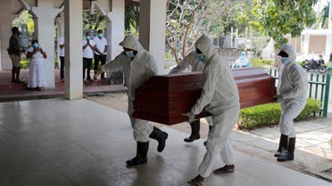 Sri Lankan health workers carry a coffin carrying remains of a COVID -19 victim to a cremation furnace as relatives watch from a distance in Colombo, Sri Lanka, Wednesday, Feb. 10, 2021. (AP)