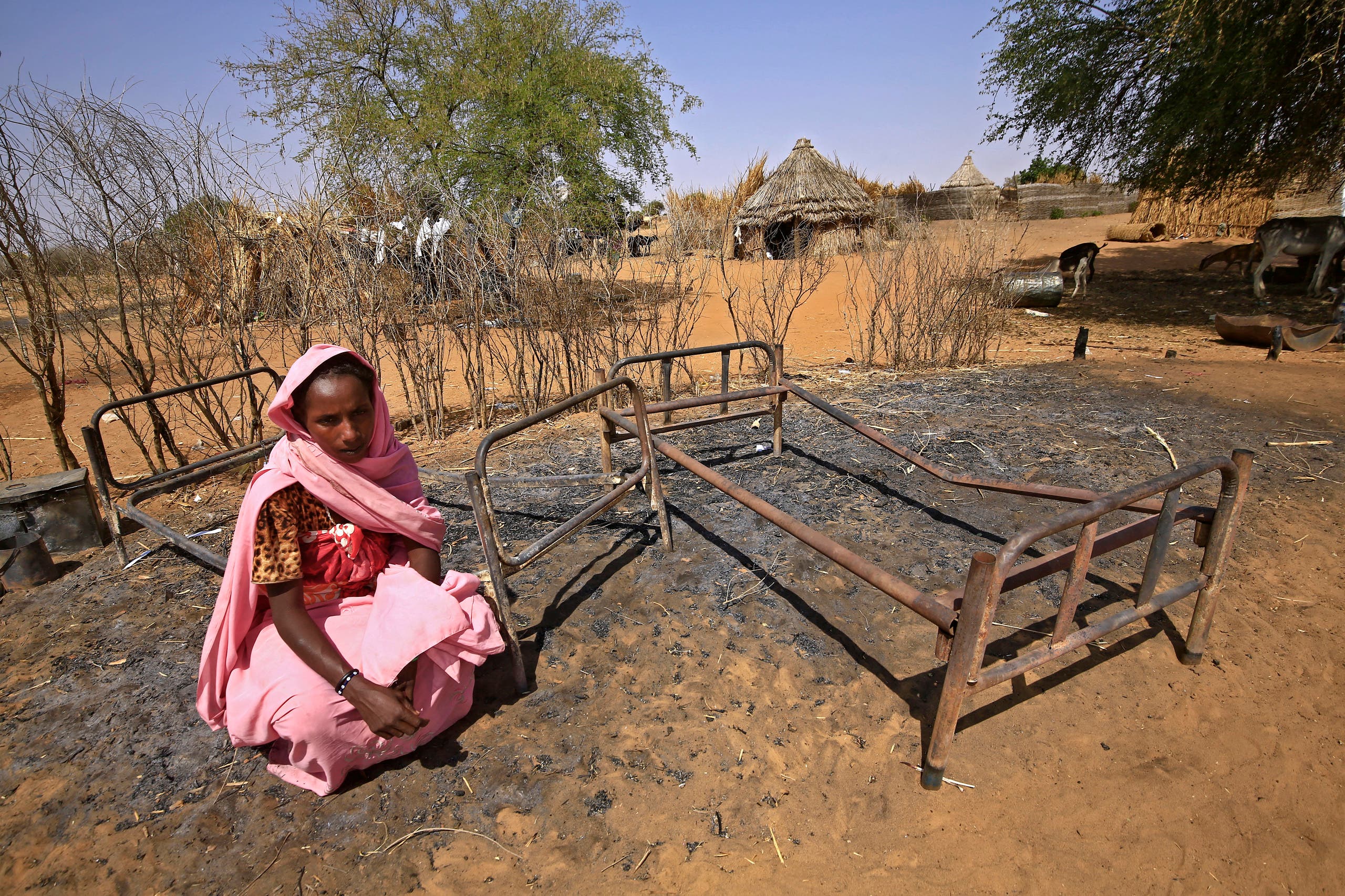 A Sudanese woman is pictured next to burnt beds following violence in the village of al-Twail Saadoun, 85 kilometres south of Nyala town, the capital of South Darfur, on February 2, 2021. (AFP)