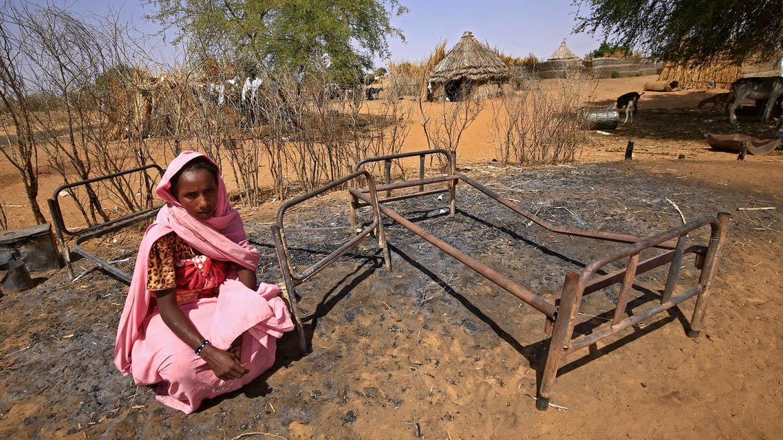 A Sudanese woman is pictured next to burnt beds following violence in the village of al-Twail Saadoun, 85 kilometres south of Nyala town, the capital of South Darfur, on February 2, 2021. (AFP)