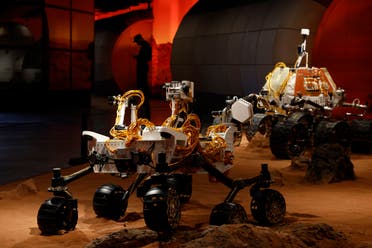 A security guard is silhouetted near a display depicting rovers on Mars during an exhibition in Beijing on Thursday, July 23, 2020. (AP Photo/Ng Han Guan)