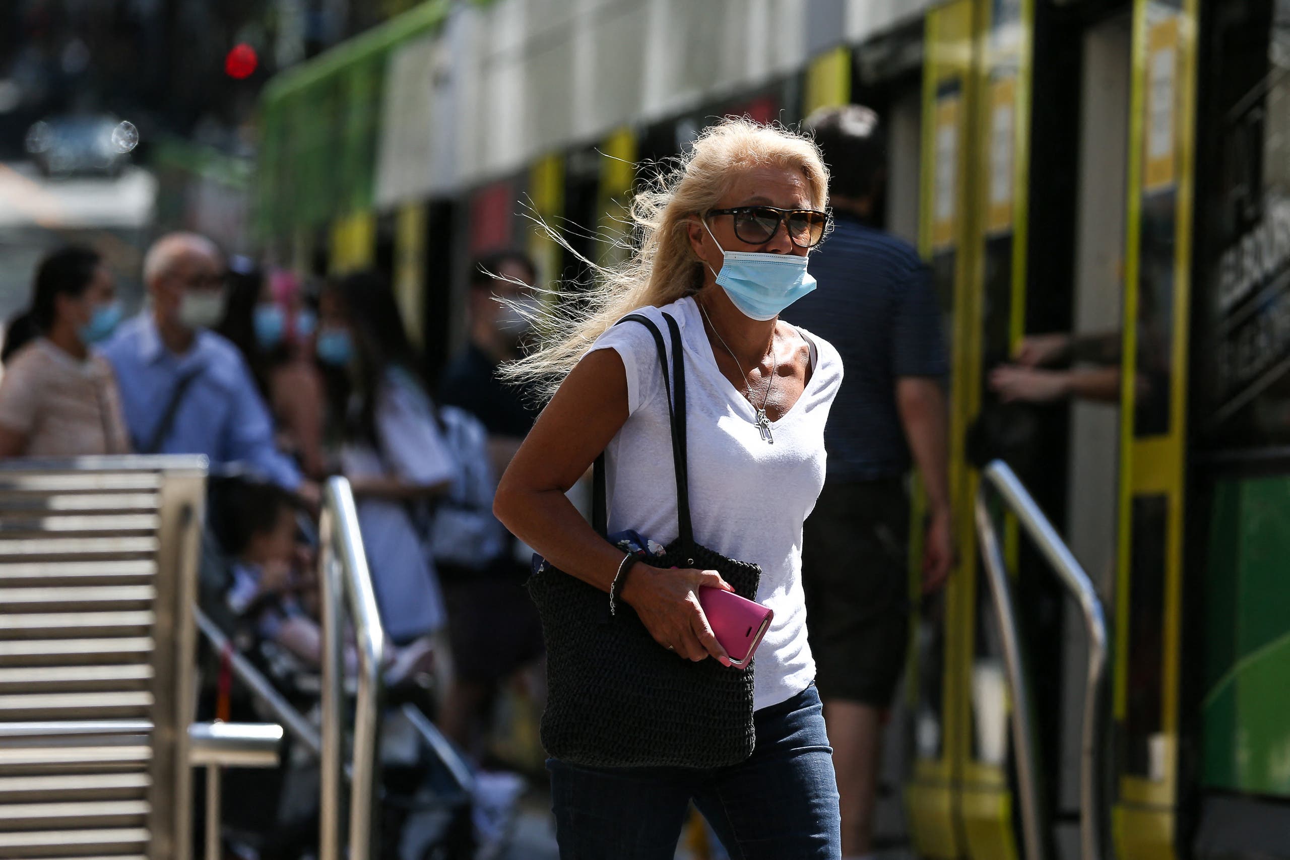 A woman wearing a face mask walks on a street in Melbourne on February 12, 2021, after authorities ordered a five-day state-wide lockdown starting at midnight local time to stamp out a new coronavirus outbreak. (AFP)