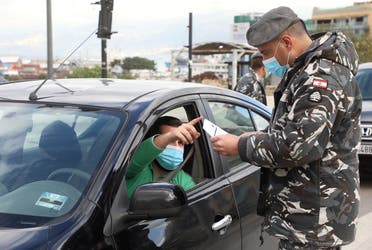 A police officer wearing a face mask talks with a driver at a checkpoint in Beirut, Jan. 15, 2021. (Reuters)