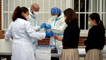 Medics collect saliva samples from pupils in a school in Madrid on December 17, 2020 for a study on coronavirus transmission between children and from children to adults. (Oscar del Pozo/AFP)