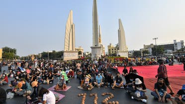 Pro-democracy protesters sit next to the numbers 112, signifying the Thai royal defamation law, spelled out with coconut shells as they take part in an anti-government rally near the Democracy Monument in Bangkok on February 13, 2021. (AFP)