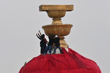 Protesters hold up the three finger salute as they wrap a part of the Democracy Monument with a large red sheet with pro-democracy messages written on it during an anti-government rally in Bangkok on February 13, 2021. (AFP)