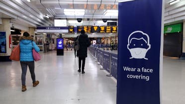 Travellers pass a Covid-19 information poster alerting them that the wearing of masks is compulsory, inside Victoria train station in central London on January 25, 2021. (AFP)