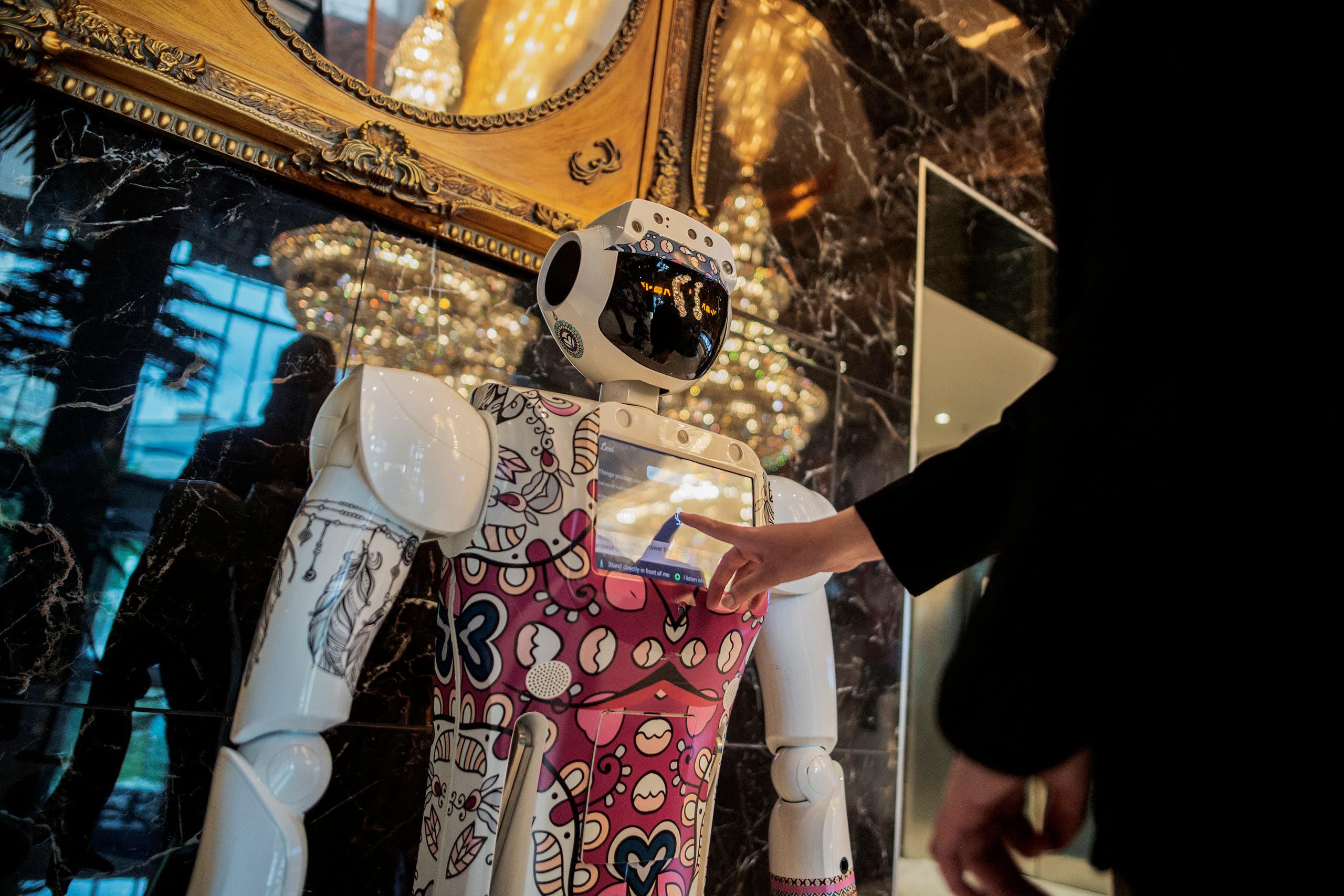 A receptionist asks for information from a robot by CTRL Robotics company in the hall of the Sky Hotel in Sandton, South Africa, on January 29, 2021. (AFP)