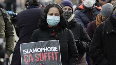 A woman holds a placard reading enough of islamophobia as protesters demonstrate against a bill dubbed as anti-separatism, in Paris on February 14, 2021. (AFP)
